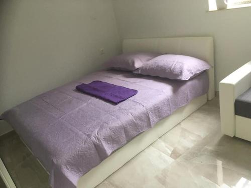 a bed with purple sheets and pillows on it at Apartman Milica in Vrgada