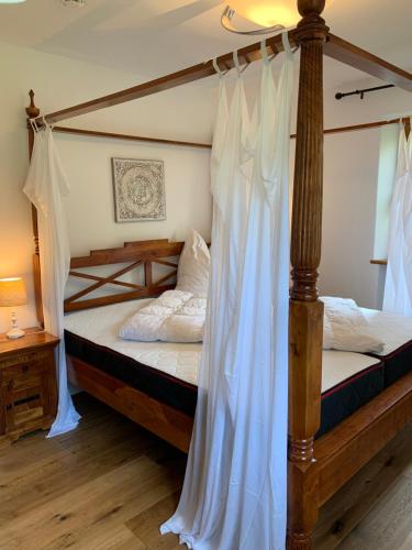 a bedroom with a four poster bed with white curtains at Ferienwohnung mit Herz Seebruck am Chiemsee in Seeon-Seebruck