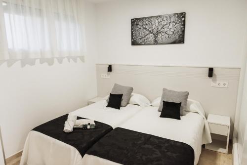 アルビールにあるNacavi Albir Aparthotelの白い壁の客室内のベッド2台