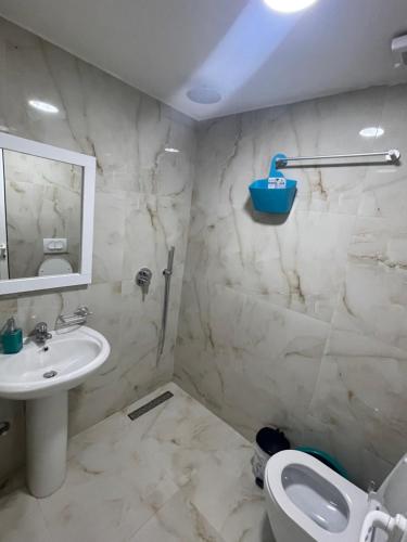 a bathroom with a sink and a toilet and a mirror at GREEN Apartments in Ksamil