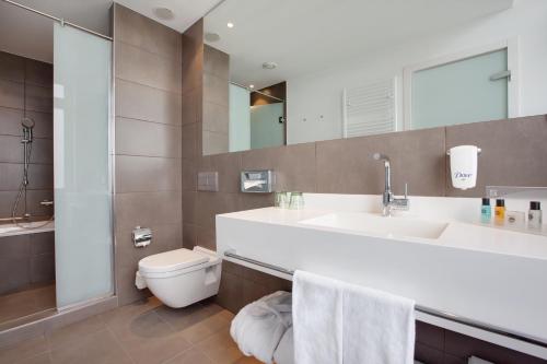 ein Badezimmer mit einem Waschbecken, einem WC und einem Spiegel in der Unterkunft Holiday Inn Dresden - Am Zwinger, an IHG Hotel in Dresden