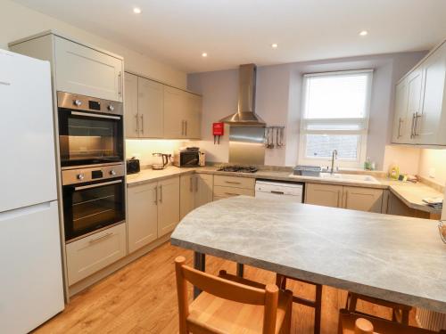 a kitchen with white appliances and a table with chairs at Cobbleken in Cockermouth