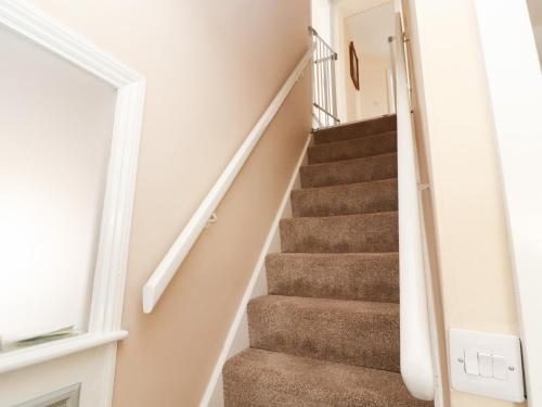 a winding staircase in a home with white walls at Cobbleken in Cockermouth