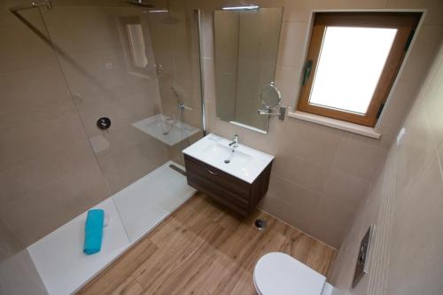 uma casa de banho com um lavatório, um chuveiro e um WC. em Casa da Ladeira Branca em Lagos