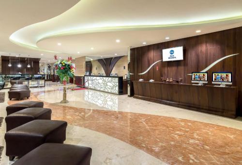 a hotel lobby with a reception desk and stools at Best Western Papilio Hotel in Surabaya