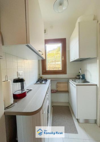 eine kleine Küche mit weißen Geräten und einem Fenster in der Unterkunft The Family Nest - Casetta con vista in Vittorio Veneto