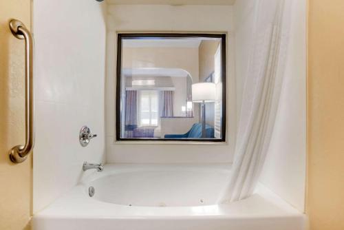 a bathroom with a tub and a mirror at Comfort Suites Tallahassee Capitol - University Area in Tallahassee