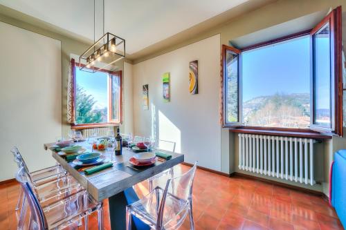 una sala da pranzo con tavolo, sedie e finestre di Anita Lake Fitness Retreat - Happy Rentals a Gemonio