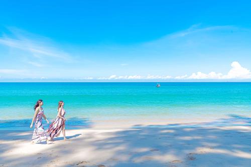 two women walking on a beach near the ocean at Cassia Phuket, part of Banyan Group in Bang Tao Beach