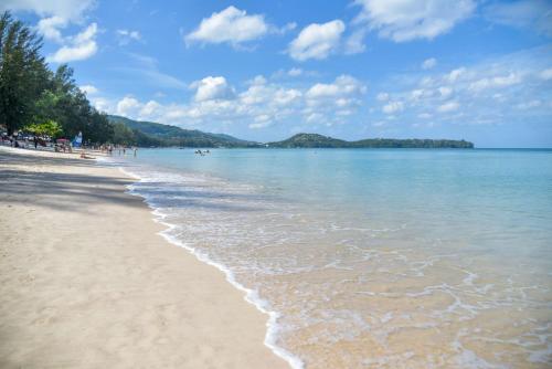 a beach with people walking on the sand and the water at Cassia Phuket, part of Banyan Group in Bang Tao Beach