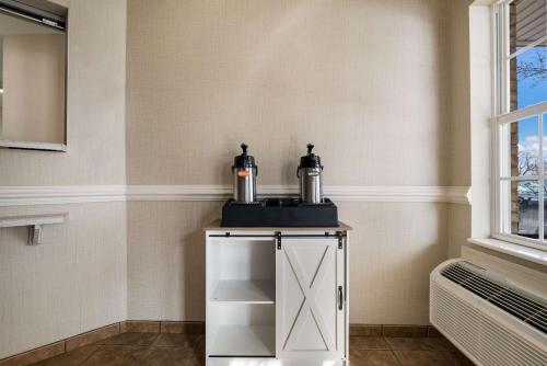 a small white cabinet with two bottles on it next to a window at Suburban Studios Denver Central-Arvada in Arvada