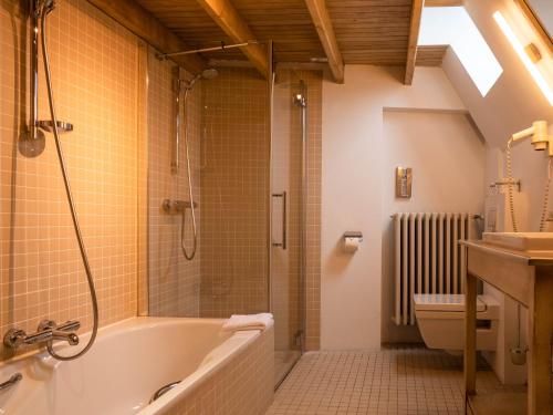 La salle de bains est pourvue d'une baignoire, d'une douche et de toilettes. dans l'établissement Hotel Monasterium PoortAckere Ghent, à Gand