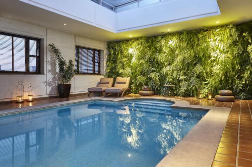 una piscina en una casa con una pared verde en L'Hotel PortoBay São Paulo, en São Paulo