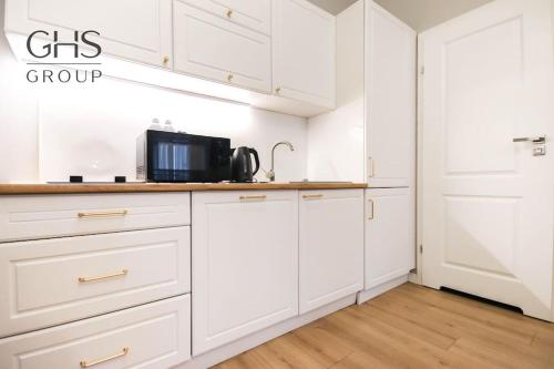 a kitchen with white cabinets and a microwave at Elegancki apartament w centrum miasta-Kazimierz in Krakow