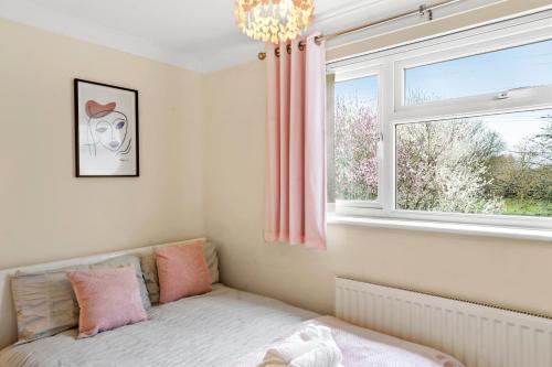 een slaapkamer met een bed en een raam met roze gordijnen bij luxury 6 bedroom house in Aylesbury, Free parking in Buckinghamshire