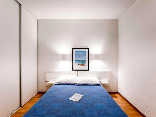 - une chambre avec un lit doté d'une couverture bleue et d'une photo dans l'établissement Apartment Les Alcyons T3 by Interhome, au Le Verdon-sur-Mer