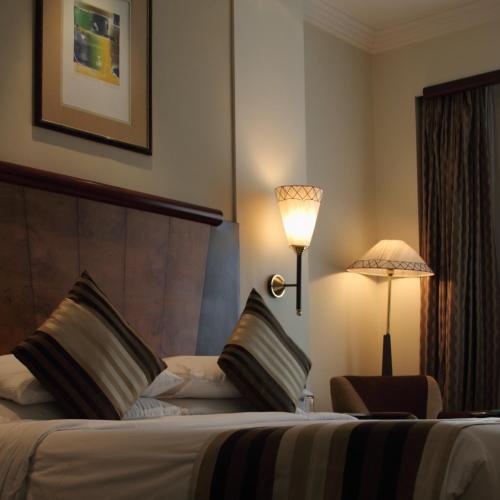 a hotel room with a bed with a lamp and a chair at The Park Kolkata in Kolkata