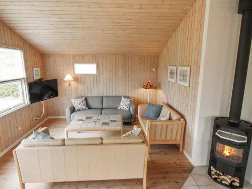 a living room with a couch and a stove at Holiday Home Dolma - 75m from the sea in NW Jutland by Interhome in Løkken