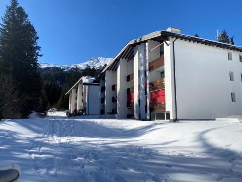 a snow covered parking lot in front of a building at Apartment Uehlinger La Riva 307 by Interhome in Lenzerheide