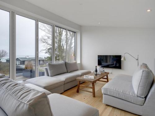 a living room with white furniture and a large window at Holiday Home Ebke - 70m from the sea in Sealand by Interhome in Gilleleje