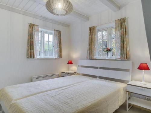 a white bedroom with a bed and two windows at Holiday Home Tabetha - 25m from the sea by Interhome in Tisvildeleje