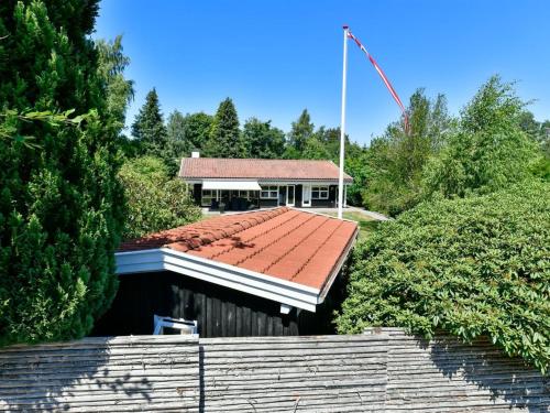 a building with a red roof with a flag on it at Holiday Home Cedomir - 625m from the sea in Sealand by Interhome in Hornbæk