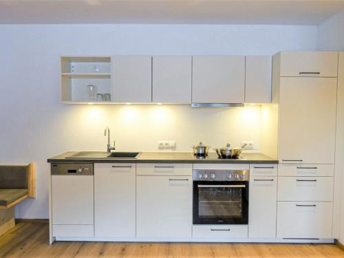 a kitchen with white cabinets and a sink and an oven at Apartment Freiheit-La by Interhome in Schnann