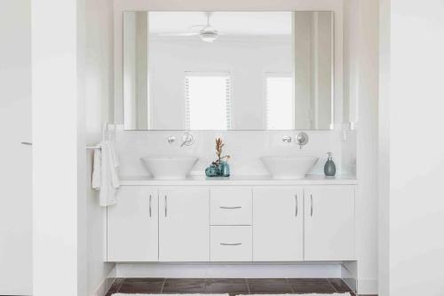 a white bathroom with two sinks and a mirror at The Oaks Country Getaway in Canowindra