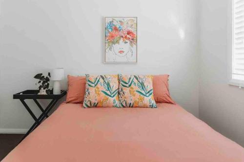 un letto con lenzuola arancioni e una foto a parete di The Oaks Country Getaway a Canowindra