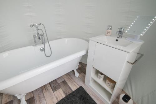 a white bathroom with a tub and a sink at Bulle à la Belle étoile in Clécy