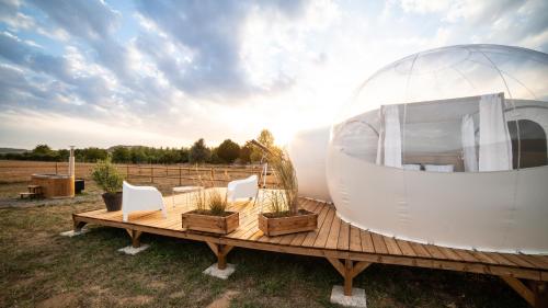 una casa en una cúpula en una terraza de madera con sillas en Bulle à la Belle étoile en Clécy
