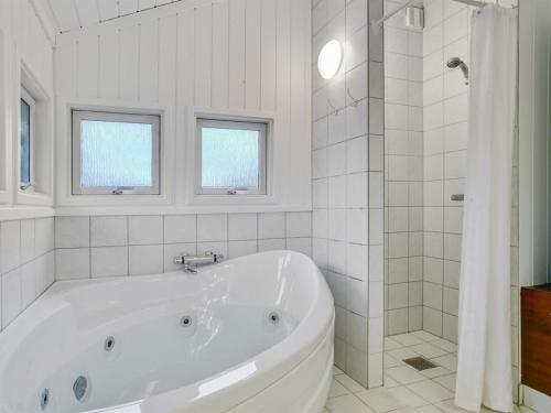 a white bathroom with a tub and a shower at Holiday Home Eivor - 500m from the sea in Sealand by Interhome in Hornbæk
