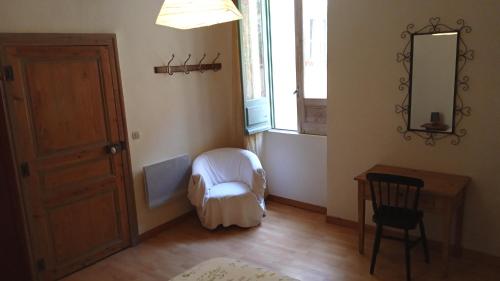 a room with a chair and a table and a mirror at Terrasse fleurie in Pézenas