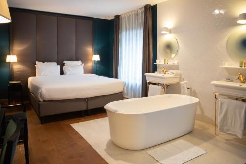 een badkamer met een bad en een bed en een bed en wastafel bij Ezia in Montlivault