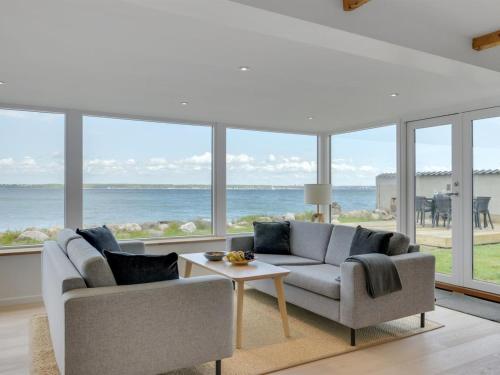 a living room with a couch and a table and windows at Holiday Home Elsabeth - 20m from the sea in Sealand by Interhome in Helsingør