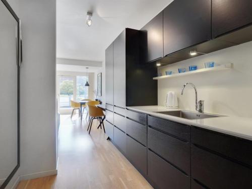 a kitchen with black and white cabinets and a table at Apartment Liv - 50m from the sea in Sealand by Interhome in Helsingør
