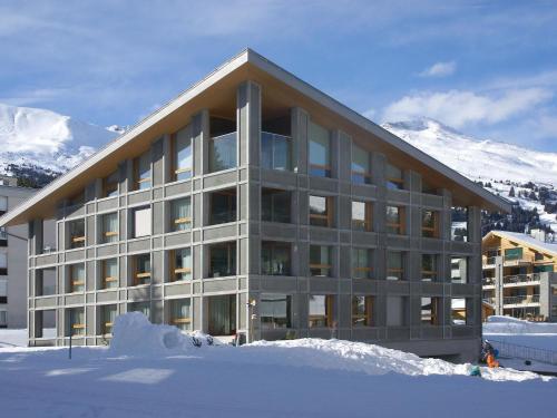 un grand bâtiment avec de la neige devant une montagne dans l'établissement Apartment Parvenda by Interhome, à Lenzerheide