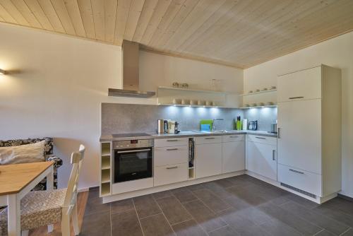 a kitchen with white cabinets and a wooden ceiling at Alb Appartements in Albstadt