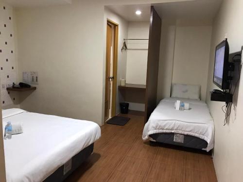 a hotel room with two beds and a television at I'm Inn Hotel Sorsogon near SM or Terminal in Sorsogon