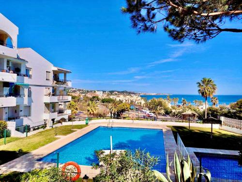 a swimming pool in front of a building and the ocean at Torrenueva , La Cala De Mijas , Vistamar , Go to costa in La Cala de Mijas