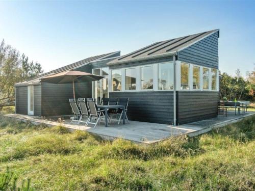 uma pequena casa com uma mesa e cadeiras num deque em Holiday Home Helin - 100m from the sea in Sealand by Interhome em Yderby