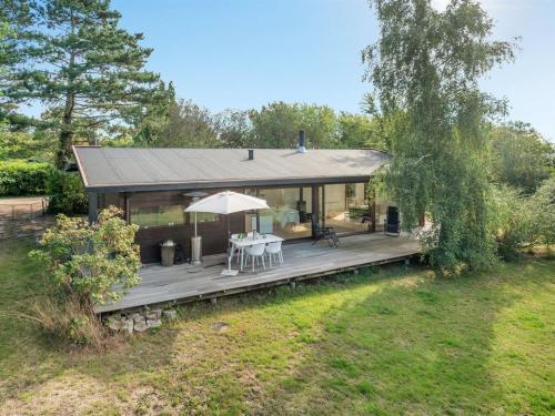 une petite cabine avec une terrasse et un parasol dans l'établissement Holiday Home Erikka - 300m to the inlet in Sealand by Interhome, à Holbæk