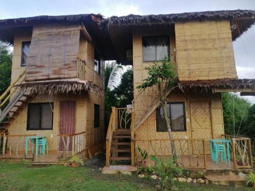 a house with two green chairs in front of it at Almare Guest House Siquijor in San Juan