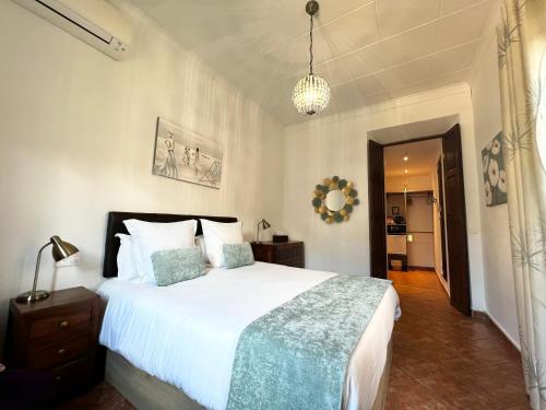a bedroom with a large white bed and a chandelier at Casa Bougainvillea in Sóller