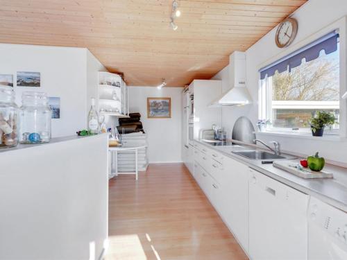 een keuken met witte kasten en een houten plafond bij Holiday Home Rico - 200m from the sea in Sealand by Interhome in Vordingborg