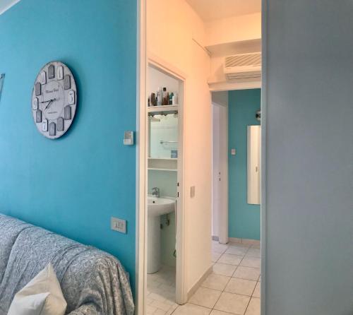 a bedroom with blue walls and a clock on the wall at Condominio Leda in Bibione