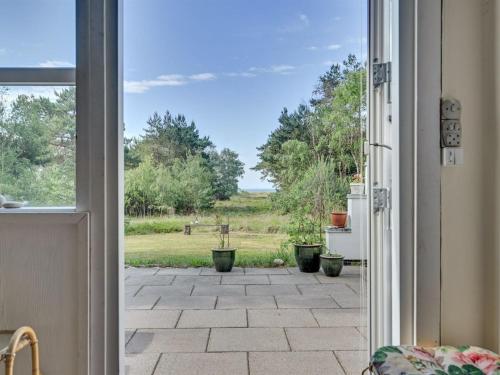 d'une porte ouverte sur une terrasse agrémentée de plantes en pot. dans l'établissement Holiday Home Claudine - 300m from the sea in Sealand by Interhome, à Tjørneholm