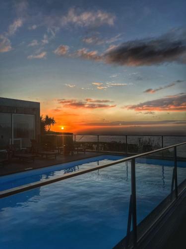a swimming pool with a sunset in the background at Mosteiros Place in Mosteiros