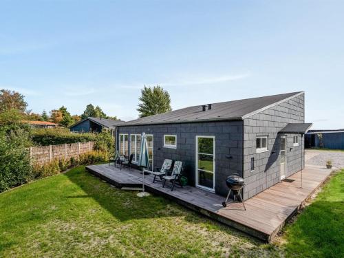 a tiny house with a deck and a grill at Holiday Home Ilkka - 175m from the sea in Sealand by Interhome in Rødvig