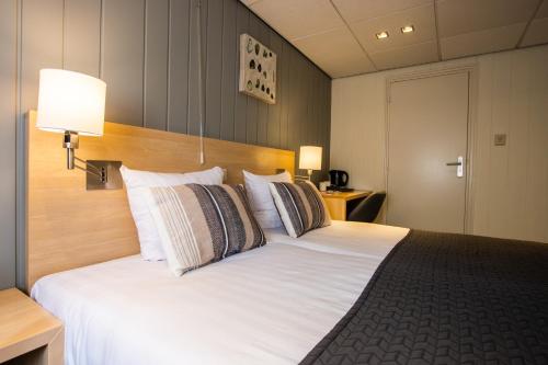 a bedroom with a large white bed with pillows at Hotel De Boei in Egmond aan Zee
